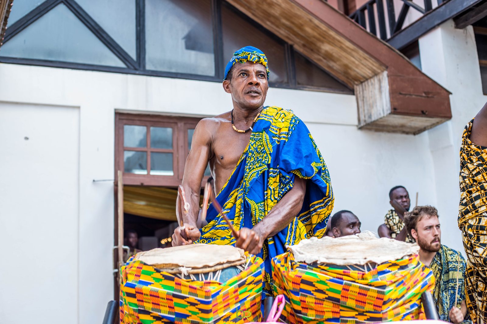 A drummer plays the talking drums in kente wraps